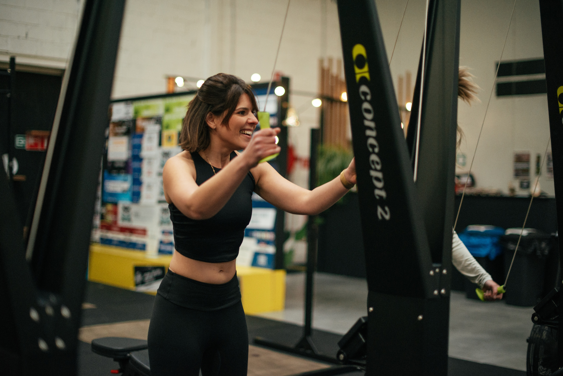 Lachende vrouw traint op een SkiErg in een CrossFit-gym