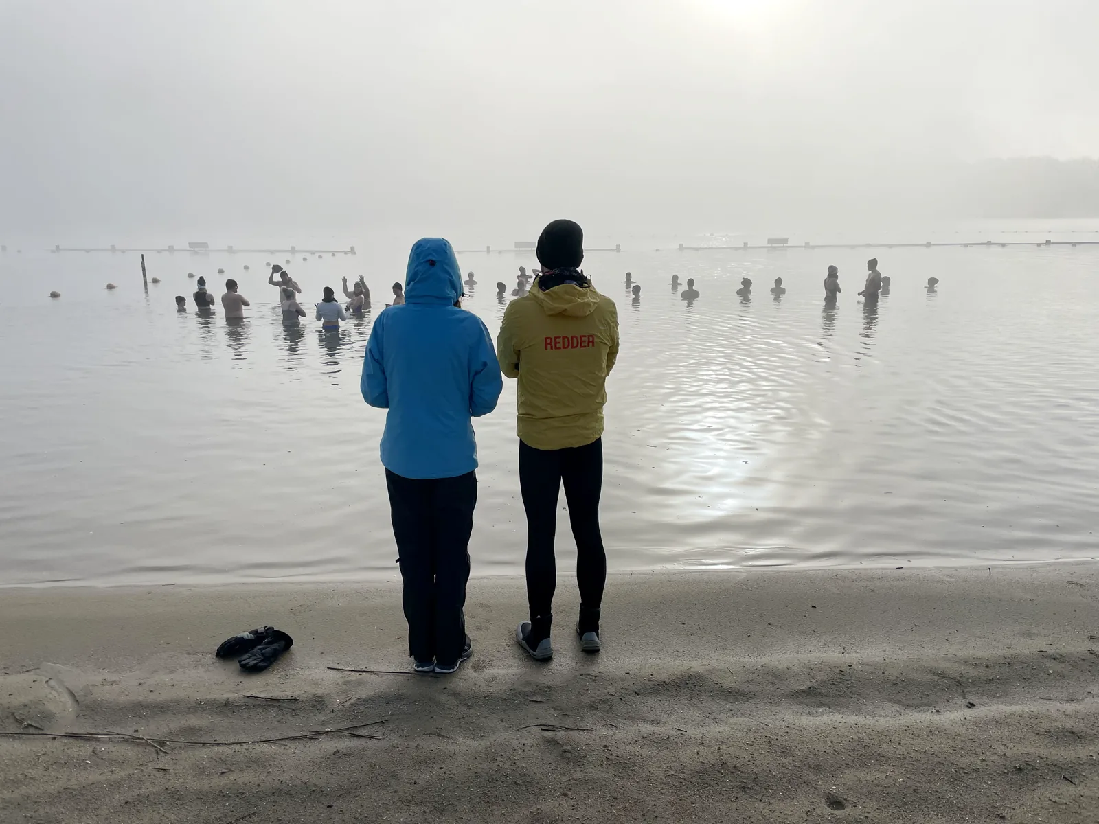 Een erkende redder houdt vanaf het strand toezicht op de dippers in het water van Nieuwdonk