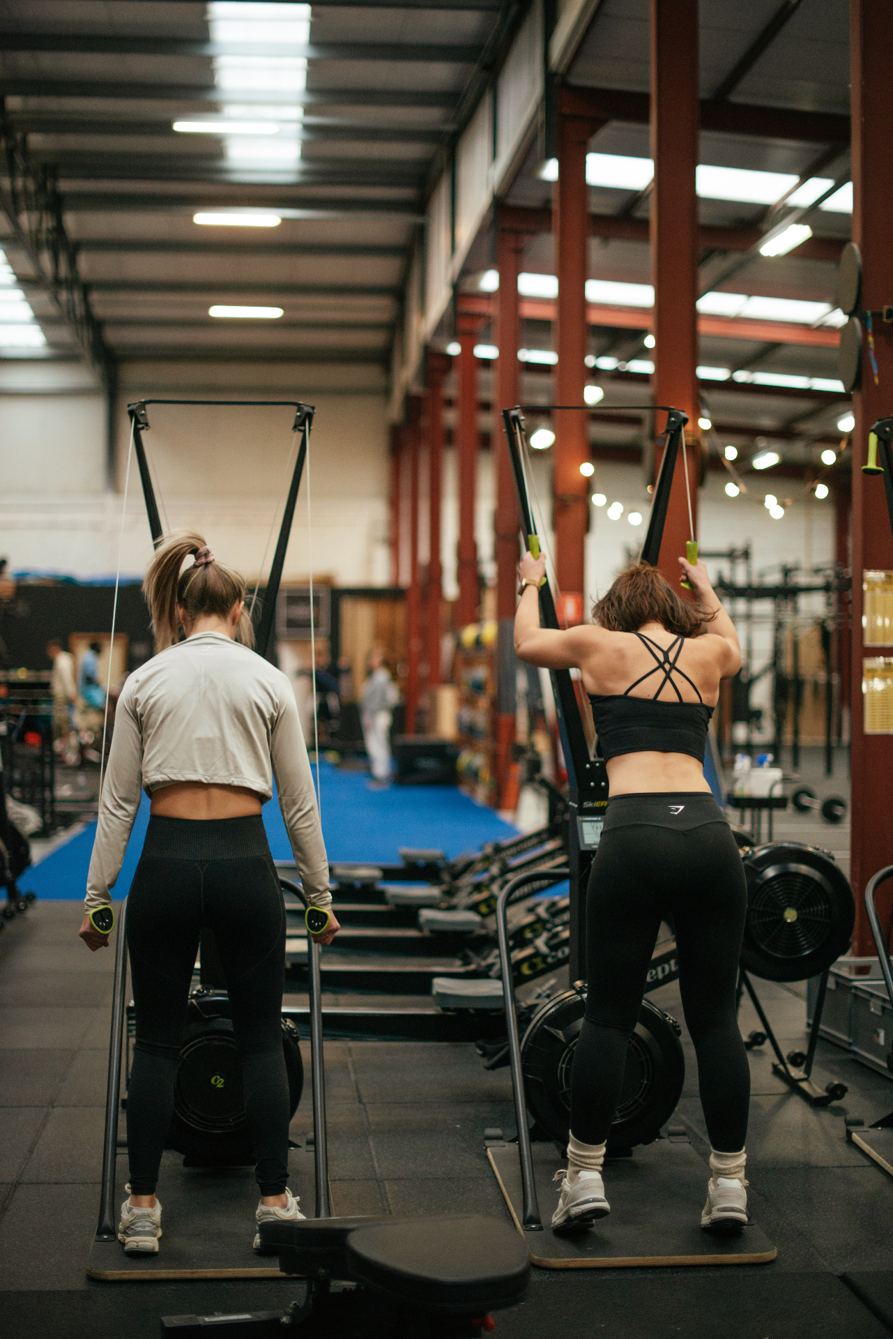 Twee atleten trainen op een SkiErg in een CrossFit-gym