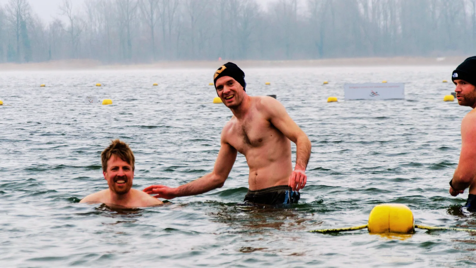 Twee deelnemers staan lachend in het koude water van Nieuwdonk