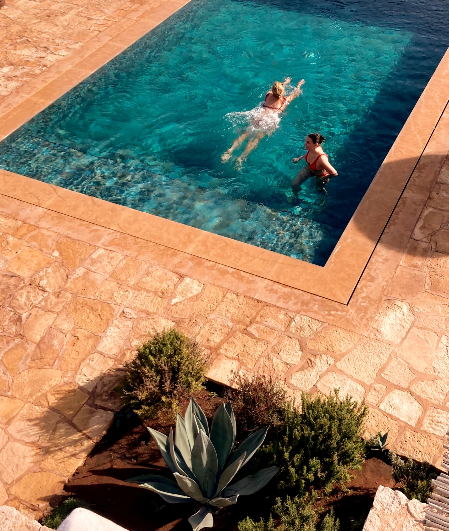 Twee vrouwen zwemmen ontspannen in een infinity pool aan de Atlantische kust